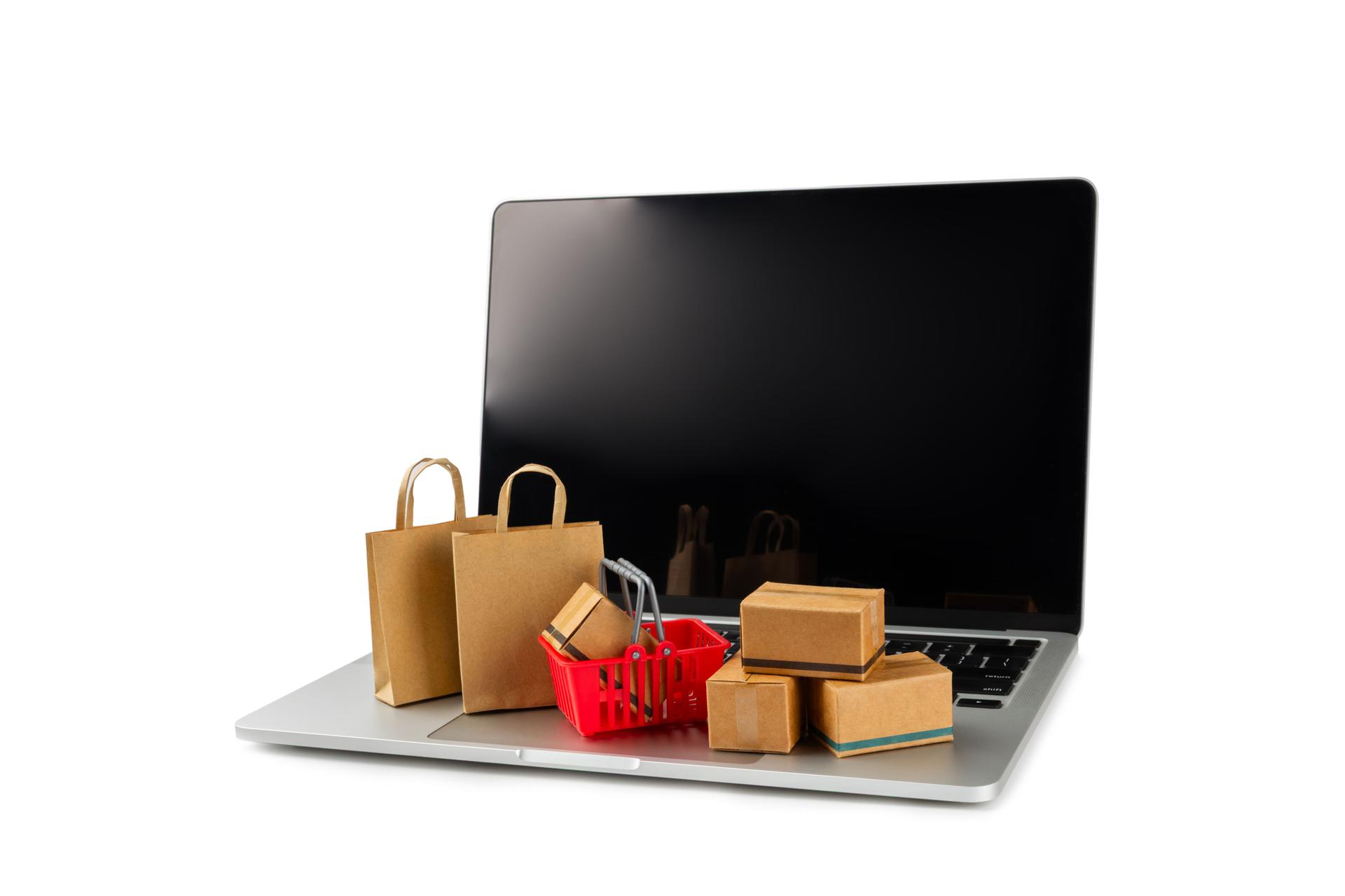 Online shopping concept.Cardboard box and shopping bags in a trolley isolated on white background. Shopping basket. Online shopping using a laptop, tablet, phone and credit card. Home delivery.